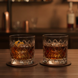 Two glasses of whiskey with lemon slices on a wooden bar counter.