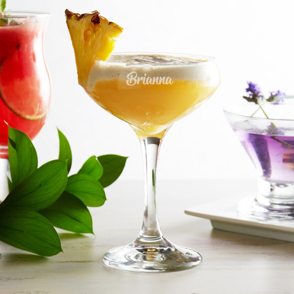 Two glasses of rose wine with a bottle on a tray, set against a blurred background.
