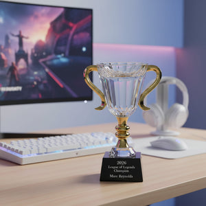 Crystal trophy with gold handles on a desk in front of a computer screen