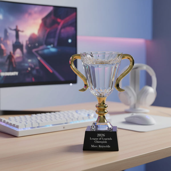 Crystal trophy with gold handles on a desk in front of a computer screen
